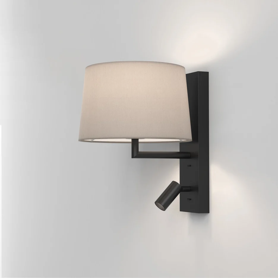 The Telegraph wall light features a sleek, modern design with an angled arm and rectangular backplate in a matt black finish. Available with a tapered shade in four colours: white, black, putty, and mocha. Shows the version with a reading lamp.