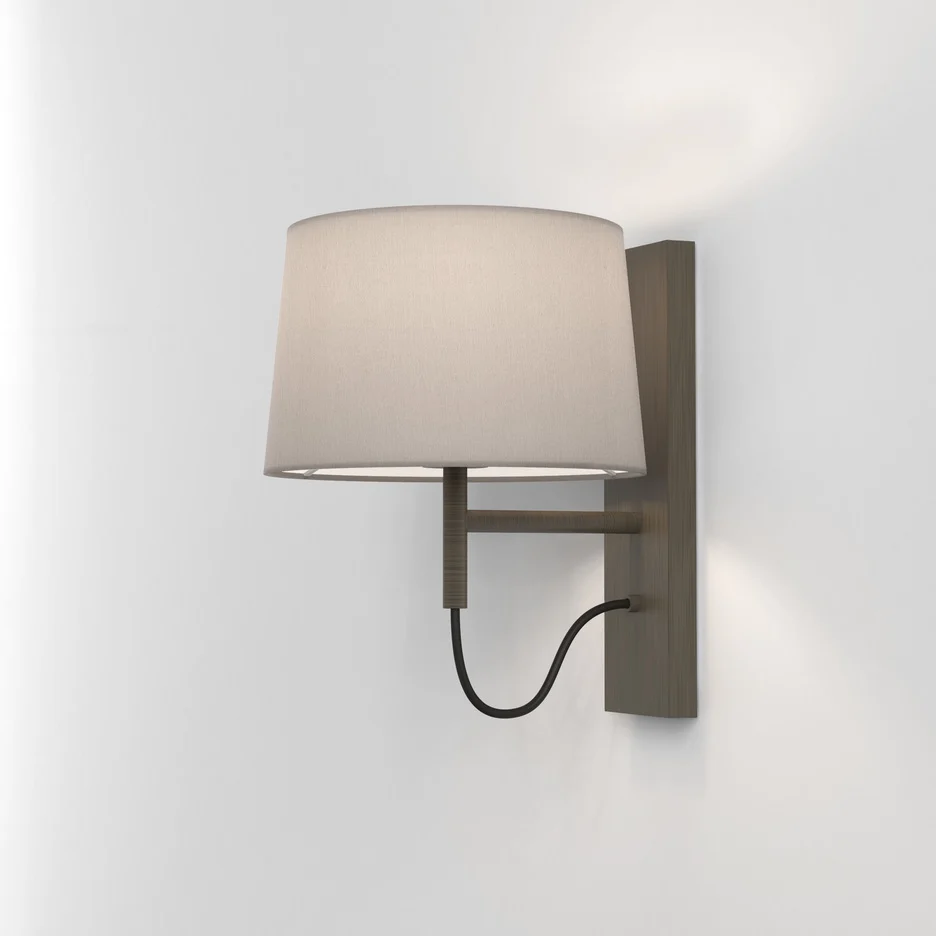 The Telegraph wall light features a sleek, modern design with an angled arm and rectangular backplate in a bronze finish. Available with a tapered shade in four colours: white, black, putty, and mocha.