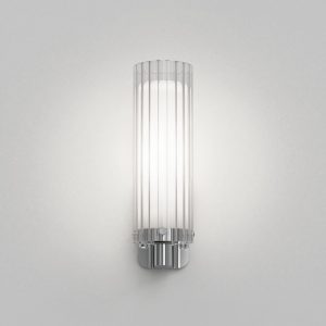 The Ottavino wall light features a modern cylindrical design with ribbed glass and a polished chrome lampholder. Shows a frontal view of the unit. IP44 rated and safe for use in bathrooms.
