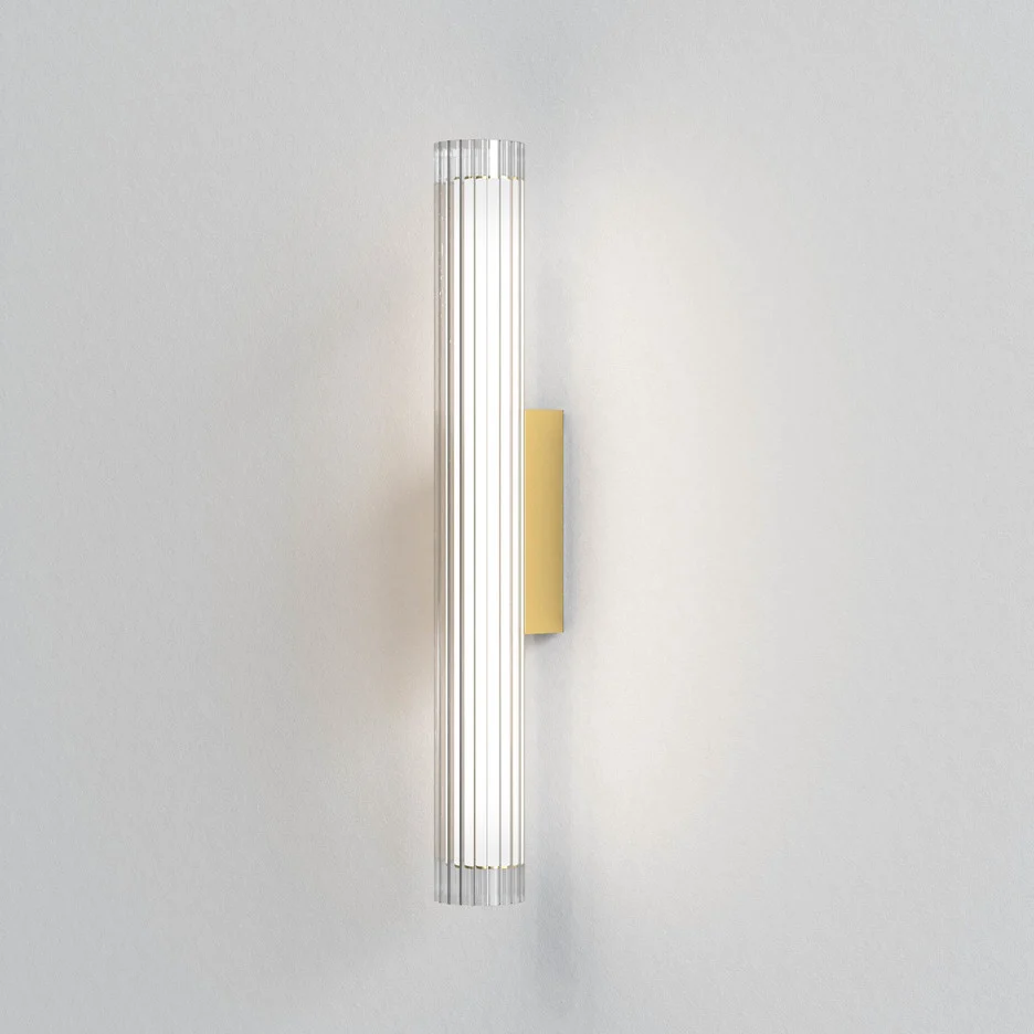 The io wall light features a modern cylindrical design with ribbed glass in a matt gold finish. IP44 rated and safe for use and bathrooms.