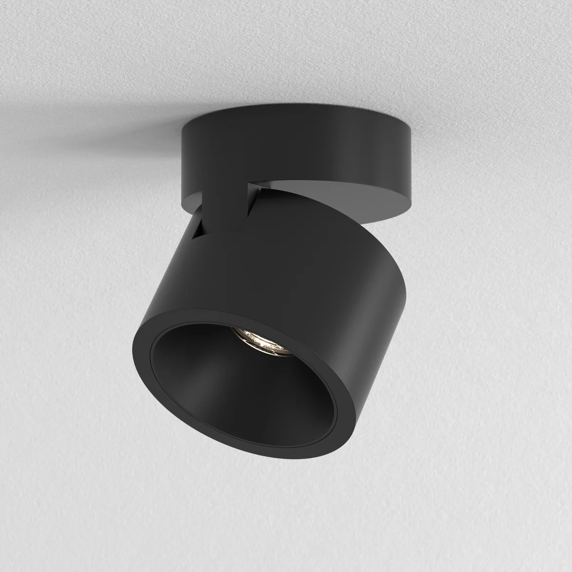 The Lynx ceiling light features a clean, minimal design with a round adjustable spotlight and round base fitted directly on a surface in a matt black finish.