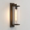 The Pimlico wall light is an outdoor light that features cylindrical glass against a rectangular backing in a bronze finish.
