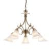 The Hardwick pendant light features elegantly curved arms in antique brass with frosted glass shades encasing 5 lamps.
