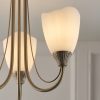 Close up of one of the Haughton ceiling light's opal glass shades and antique brass, decorative arms.
