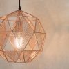 Shows a close up of the Armour pendant light which features a geometric design with alternating triangle shapes with mesh or as a clear cut out in a copper finish.