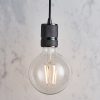 Shows the Urban pendant light against a simple marbled backdrop. The pendant features an industrial design, with a lamp holder that has knurled detailing in modern black and a braided black suspension cable.