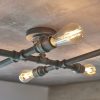 The Pipe ceiling light features an industrial design with a 6-light crossbar in an aged pewter finish with exposed LED lamps at each end. Shows a close up of the LED filament bulbs and lampholders.