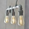 Close up of the Pipe pendant light, which has an authentic industrial design with 3 lamps on exposed pipe with aged pewter finish.