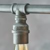 Close up of one of the Pipe pendant light's lamp holders, showing the detail of the authentic industrial design and exposed pipe with aged pewter finish.