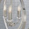 Close up of the Ritz pendant light which features a highly polished bright nickel metalwork, encrusted with thousands of clear faceted reflective details. The spherical cage encloses 3 lamps. Shows the pendant against a grey backdrop.
