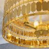 Shows a close up of the Eldora ceiling light. Features an ornate design, with hundreds of suspended hexagonal plates in gold plate finish, enclosing 3 lamps.
