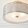 Close up of the Cordero ceiling light which features a satin nickel metal outer shade with a laser cut circle pattern and a white inner fabric shade. The bottom of the inner shade has a frosted glass diffuser enclosing three lamps.