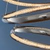 Close up of the Ozias pendant light, which features five polished chrome hoops and an integrated 97.27w LED enclosed within clear crystals that diffuse the light. Shows the detail of the crystal diffuser.