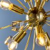 Close up of the Miro pendant light features a central suspended sphere with multiple rods extended outward from it, supporting both beautiful crystal cubes and lamps in a polished brass finish.