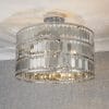 Shows the Eldora ceiling light installed in a simple room, showing the lighting effects. Features an ornate design, with hundreds of suspended hexagonal plates in silver plate finish, enclosing 3 lamps.
