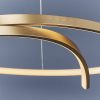 Close up of the Rafe pendant light in a room with a blue backdrop. The pendant features an elegant twisted hoop with integrated inner LED in a matt brushed gold finish.