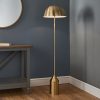 Shows the Nova floor light on in a simple room. The light features a simple, modern design with a half spherical lampshade and a highly polished antique brass finish. Complete with inline foot switch.
