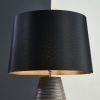 Shows the Isla lampshade fitted onto a table lamp base. The lampshade features a contemporary, tapered design in silk lined with black cotton fabric, available in ø16 inch size.