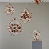 Shows the Muni product range in copper. The pendants, ceiling, and table light all feature a striking spherical design with metal arms in copper. A mix of copper and clear spheres hang from the fittings at various heights. The three pendants are available in ⌀39cm, ⌀48cm, and ⌀60cm sizes.