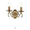The Bernice wall light has two curved arms finished in antique brass, supporting two traditional lampholders on either side. A pull cord switch hangs in the centre.