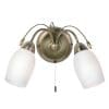 The Meadow wall light has delicate, stem-like arms finished in antique brass effect plate, with opal glass shades which encase two lamps on either side. A pull cord switch hangs in the centre.