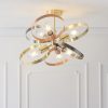The Hoop ceiling light features six lights with interwoven hoops in a mix of brushed nickel, brass, and copper finishes. The LED bulbs are set centrally in each hoop. Shows the light installed in a room.